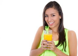 Closeup portrait of a young beautiful female holding a glass of orange juice, isolated on white background. Nutrition weight loss program.