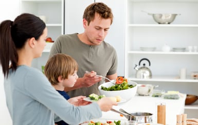 Dad serving salad to his family for lunch in the kitchen